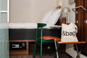 hotellrum-med-grön-stol-skrivbord-bordslampa-och-säng