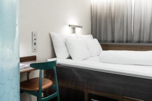 hotellrum-med-säng-vita-sängkläder-och-skrivbord-med-stol